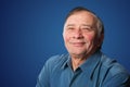 Senior man with a friendly smile standing against a dark blue ba Royalty Free Stock Photo