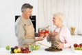 Senior Man Giving Birthday Gift To Wife Standing In Kitchen Royalty Free Stock Photo