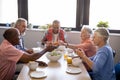 Senior man giving food to friends sitting at table