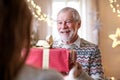 Senior man giving present to unrecognizable woman indoors at home at Christmas. Royalty Free Stock Photo