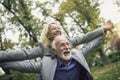 Senior man giving woman piggyback ride through park Royalty Free Stock Photo