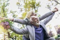 Senior man giving woman piggyback ride through park Royalty Free Stock Photo