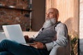 senior man with a glass of wine using his laptop .