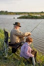 Senior man and grandson fishing on river or lake, having thermos with tea Royalty Free Stock Photo