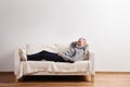 Senior man in gray sweater lying on sofa, studio shot. Royalty Free Stock Photo