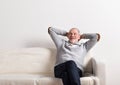 Senior man in gray sweater sitting on sofa, studio shot. Royalty Free Stock Photo