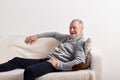 Senior man in gray sweater sitting on sofa, studio shot. Royalty Free Stock Photo