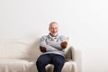 Senior man in gray sweater sitting on sofa, studio shot. Royalty Free Stock Photo