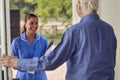 Senior Man Greeting Female Nurse Or Care Worker Making Home Visit In Uniform At Door Royalty Free Stock Photo