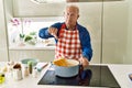 Senior man with grey hair cooking spaghetti at home kitchen with angry face, negative sign showing dislike with thumbs down, Royalty Free Stock Photo