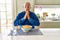 Senior man with grey hair eating pasta spaghetti at home begging and praying with hands together with hope expression on face very Royalty Free Stock Photo