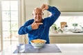 Senior man with grey hair eating pasta spaghetti at home smiling making frame with hands and fingers with happy face Royalty Free Stock Photo