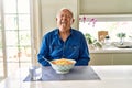 Senior man with grey hair eating pasta spaghetti at home sticking tongue out happy with funny expression Royalty Free Stock Photo