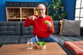 Senior man with grey hair eating salad and green apple pointing finger to one self smiling happy and proud Royalty Free Stock Photo