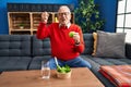 Senior man with grey hair eating salad and green apple screaming proud, celebrating victory and success very excited with raised Royalty Free Stock Photo