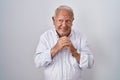 Senior man with grey hair standing over isolated background laughing nervous and excited with hands on chin looking to the side Royalty Free Stock Photo