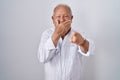 Senior man with grey hair standing over isolated background laughing at you, pointing finger to the camera with hand over mouth, Royalty Free Stock Photo