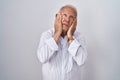 Senior man with grey hair standing over isolated background tired hands covering face, depression and sadness, upset and irritated