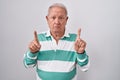 Senior man with grey hair standing over white background pointing up looking sad and upset, indicating direction with fingers, Royalty Free Stock Photo