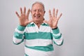 Senior man with grey hair standing over white background showing and pointing up with fingers number ten while smiling confident Royalty Free Stock Photo