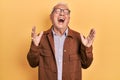 Senior man with grey hair wearing casual jacket and glasses celebrating mad and crazy for success with arms raised and closed eyes Royalty Free Stock Photo
