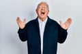 Senior man with grey hair wearing casual style and glasses celebrating mad and crazy for success with arms raised and closed eyes Royalty Free Stock Photo