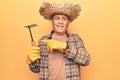 Senior man with grey hair wearing gardener hat holding rake smiling happy pointing with hand and finger Royalty Free Stock Photo