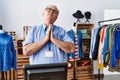 Senior man with grey hair working as manager at retail boutique begging and praying with hands together with hope expression on