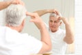 Senior man with hair loss problem looking in mirror Royalty Free Stock Photo