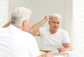 Senior man with hair loss problem looking in mirror Royalty Free Stock Photo