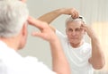 Senior man with hair loss problem looking in mirror Royalty Free Stock Photo