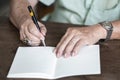 Senior man hand writing letter on ivory colour paper, Notebook,  A black mix silver pen, On wooden background, Art creative idea Royalty Free Stock Photo