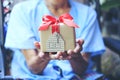 Senior man hands holding gift box with red ribbon and house model with keys, Gift new home and Real estate concept Royalty Free Stock Photo