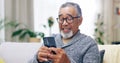 Senior man, happy and phone on couch for texting, reading or thinking for contact in home living room. Elderly person Royalty Free Stock Photo