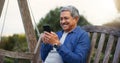 Senior man, happy and smartphone on bench for communication, connection and social media in park. Mature pensioner Royalty Free Stock Photo