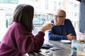 Senior man having a conversation with woman drinking coffee and relaxing, chatting at restaurant Royalty Free Stock Photo