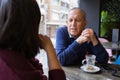 Senior man having a conversation with woman drinking coffee and relaxing, chatting at restaurant Royalty Free Stock Photo