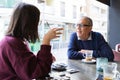 Senior man having a conversation with woman drinking coffee and relaxing, chatting at restaurant Royalty Free Stock Photo