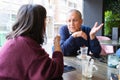 Senior man having a conversation with woman drinking coffee and relaxing, chatting at restaurant Royalty Free Stock Photo