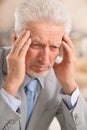 Portrait of senior man with headache holding hands on forehead at home Royalty Free Stock Photo