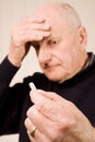 Senior man with headache holding tablet or pill Royalty Free Stock Photo