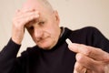 Senior man with headache holding tablet or pill Royalty Free Stock Photo
