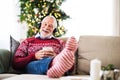 A senior man with headphones listening to music at home at Christmas time.