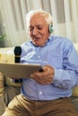 Senior man in headphones singing karaoke, using digital tablet Royalty Free Stock Photo