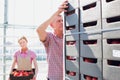 Senior man helping young female farmer arranging tomatoes in crate at greenhouse Royalty Free Stock Photo