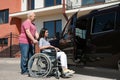 Senior man helping young woman in wheelchair to get into van Royalty Free Stock Photo