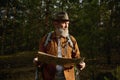 Senior man hiker looking in paper map searching rout in forest