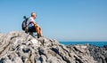 Senior man hiking looking at sea landscape sitting on rocks