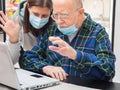 Senior man and his caregiver are doing a videocall with laptop at home Royalty Free Stock Photo