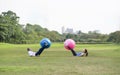 senior man and his daughter is enjoy doing exercise legs with gym ball in green nature park